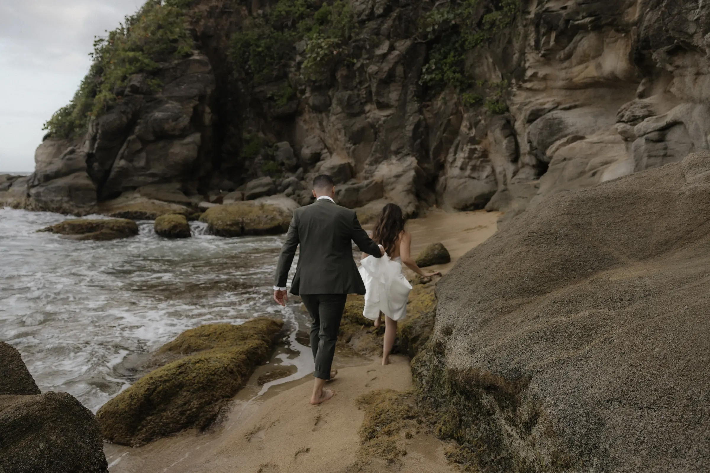 Couple walking hand in hand along a rocky coastal path