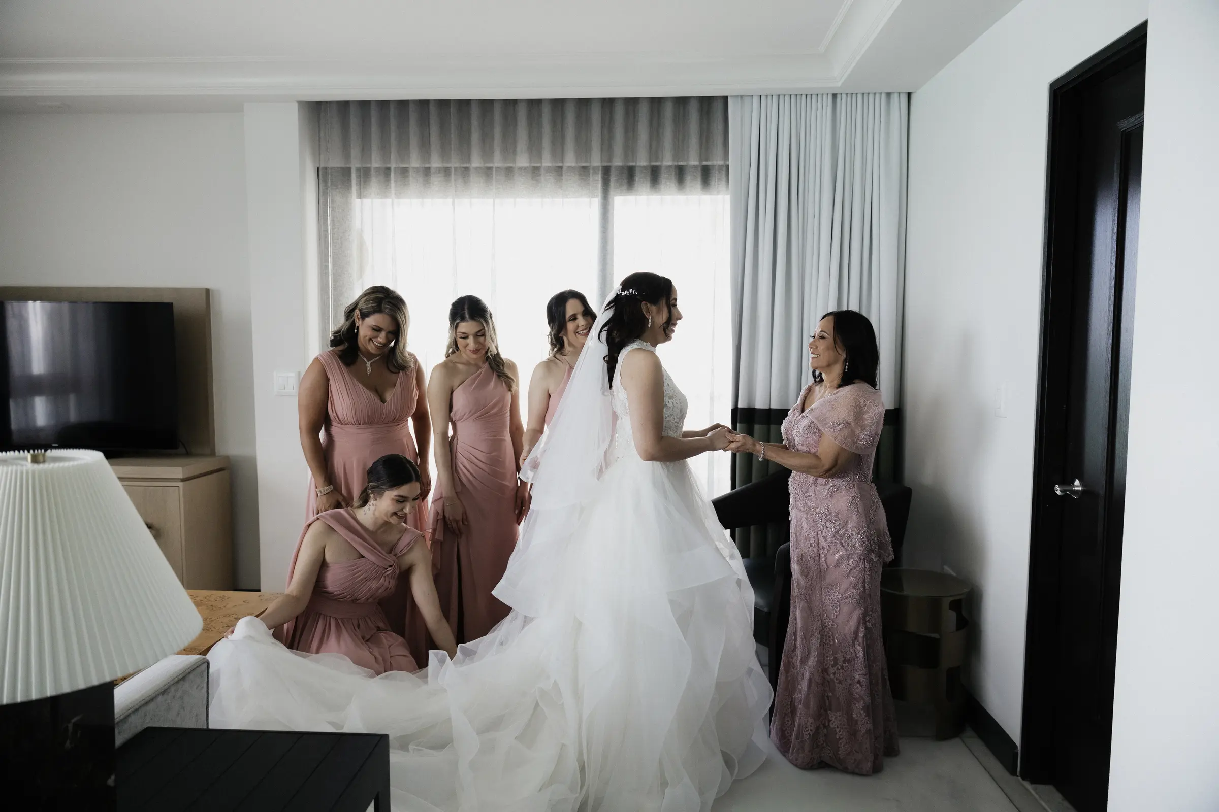 Bridesmaids helping the bride get ready in a hotel room