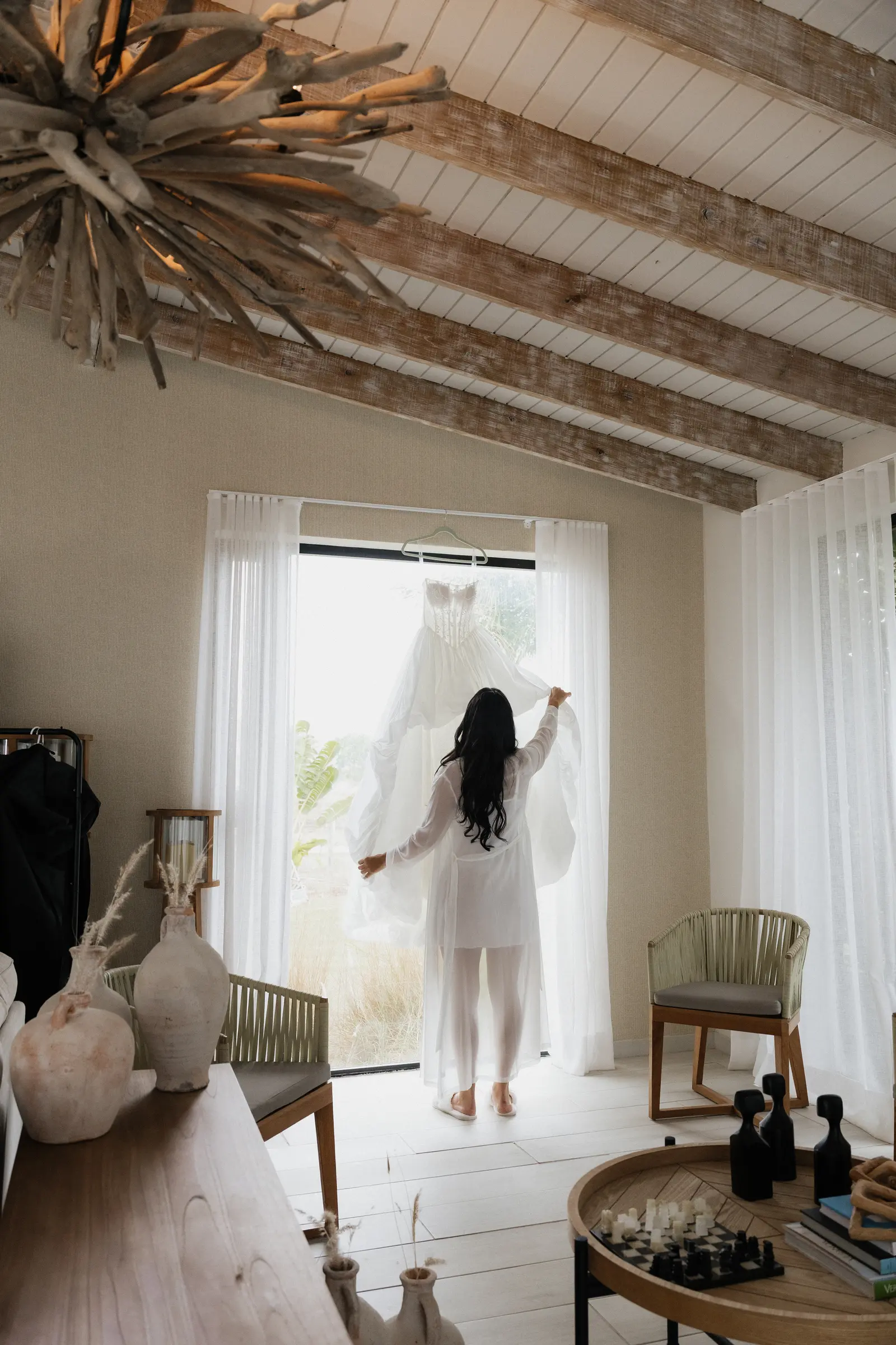 Bride reaching for her wedding dress hanging in a doorway