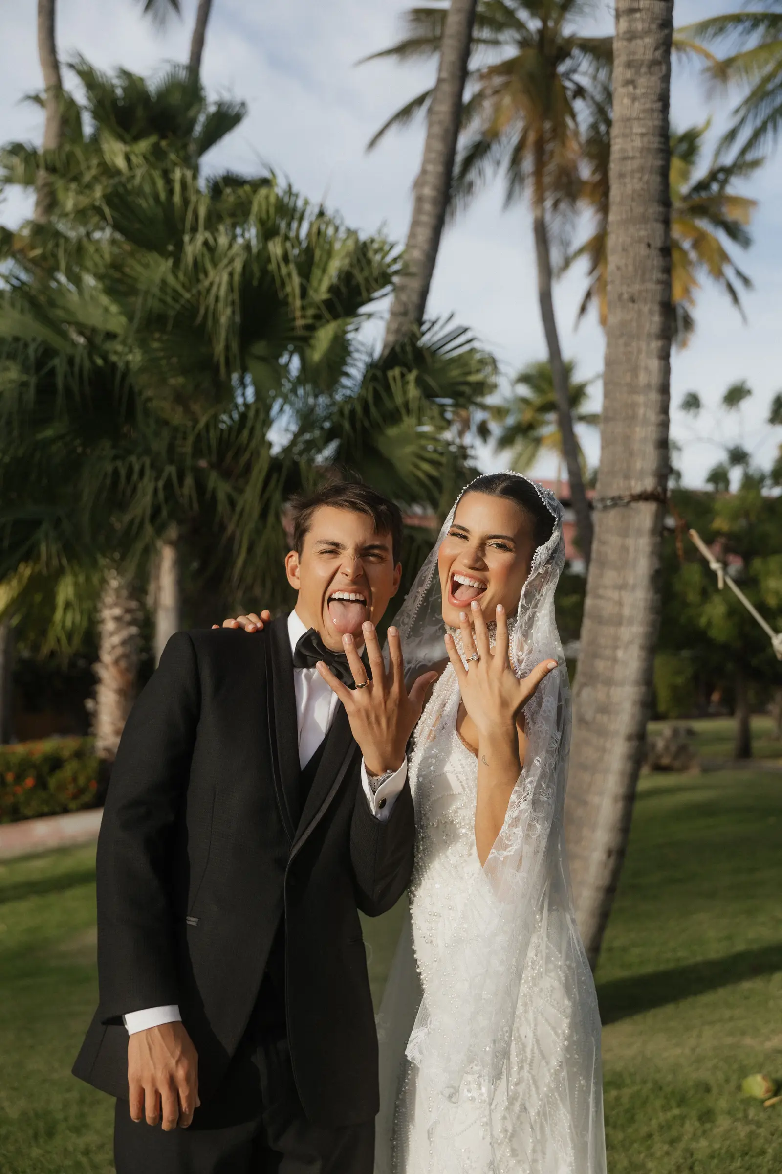 Bride and groom laughing together outdoors with palm trees