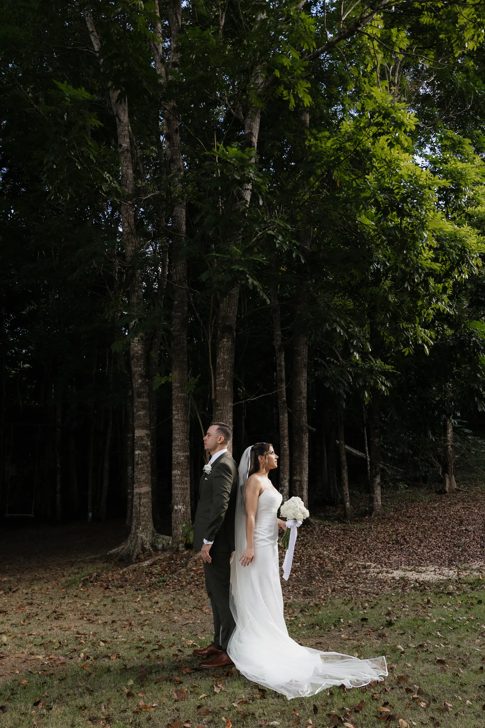 Bride and groom walking together through a wooded path