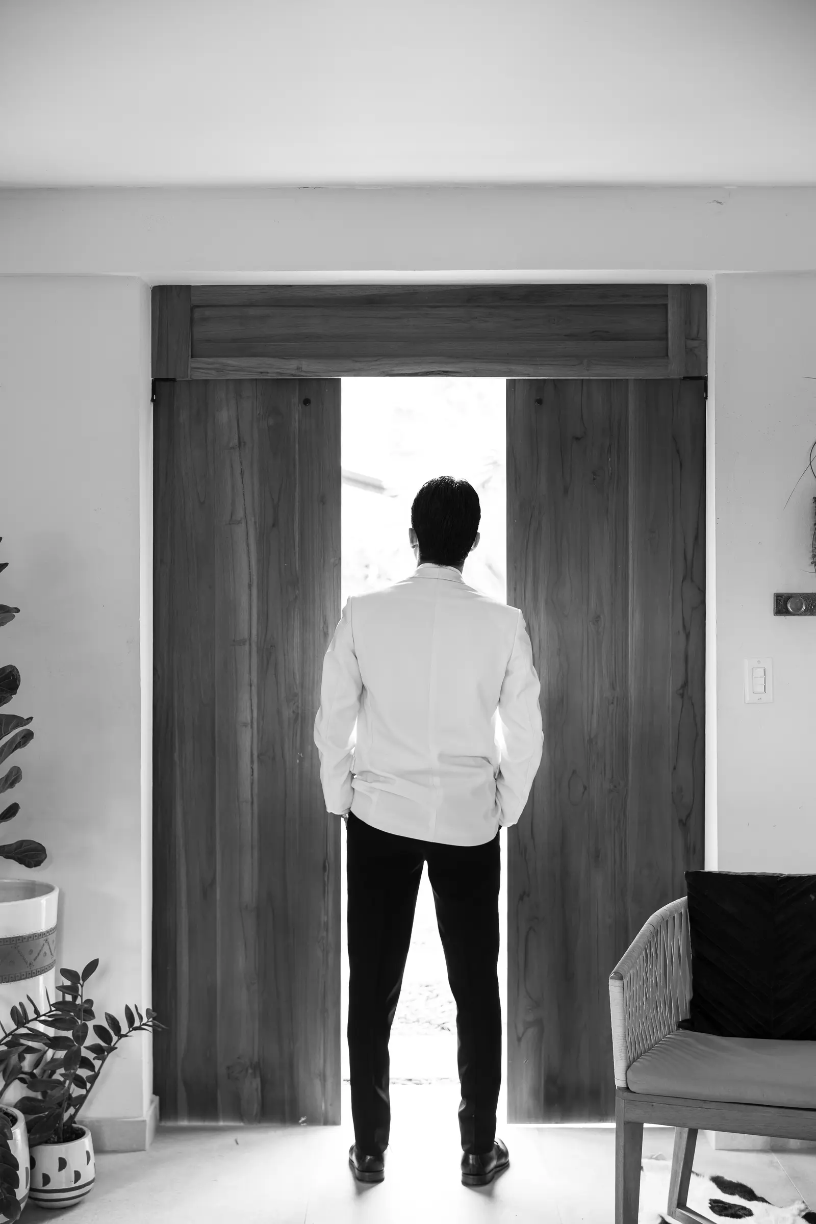 Groom standing in a doorway looking outside