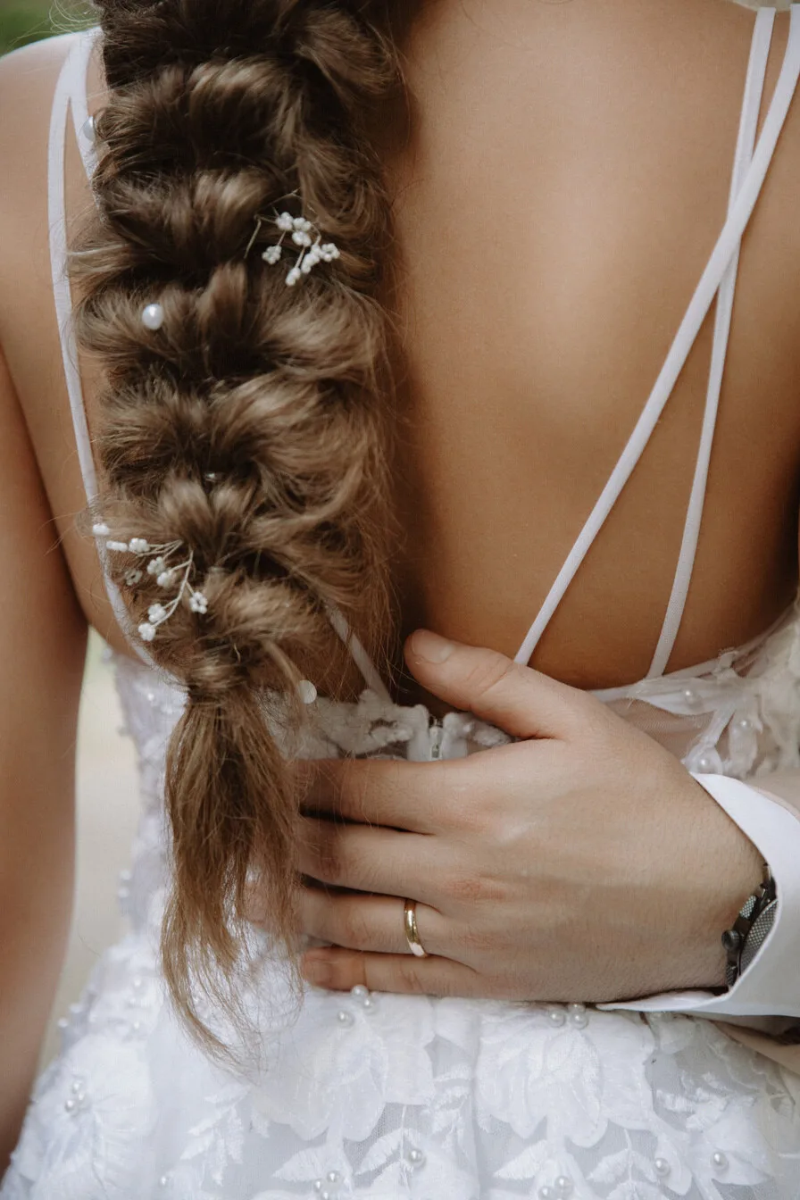 Close-up of the bride's braided hairstyle and open-back dress