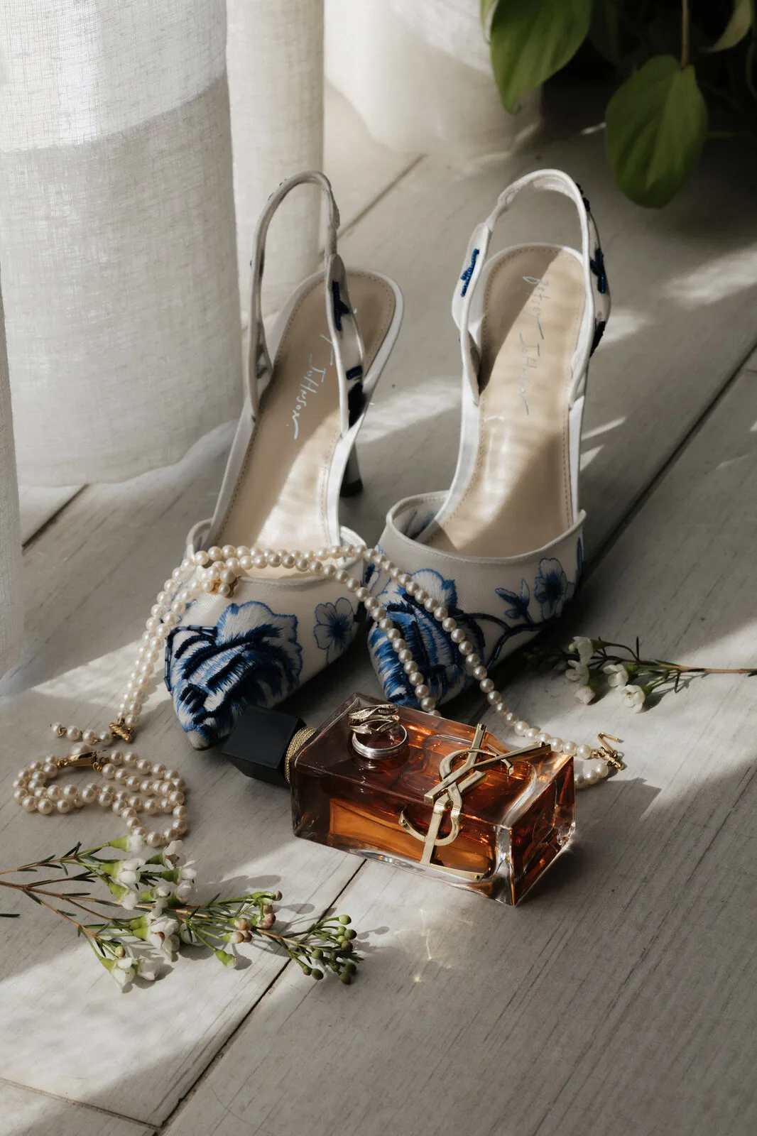 Wedding-day flatlay of embroidered shoes, perfume, and rings