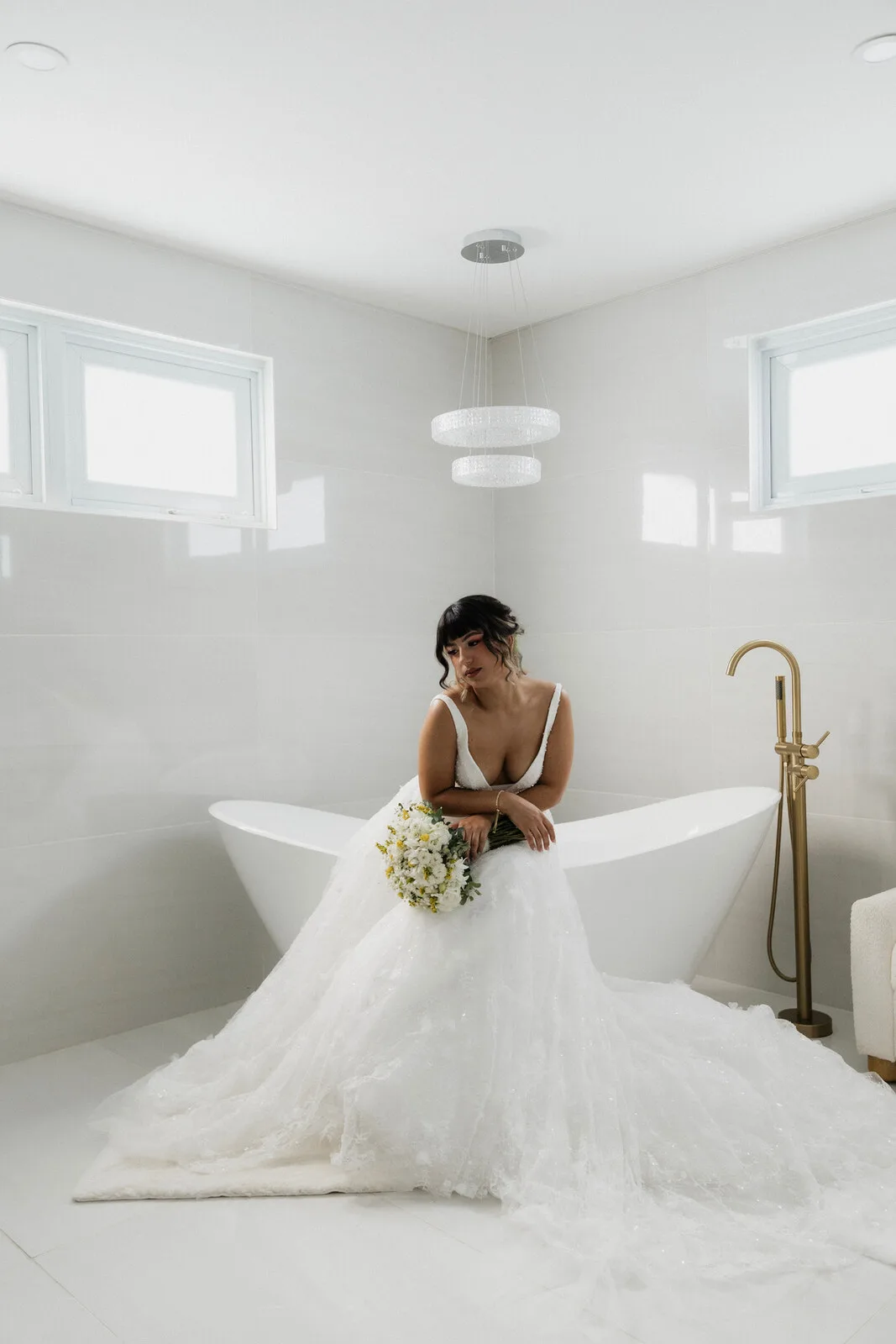 Bride sitting in a freestanding bathtub in her wedding dress