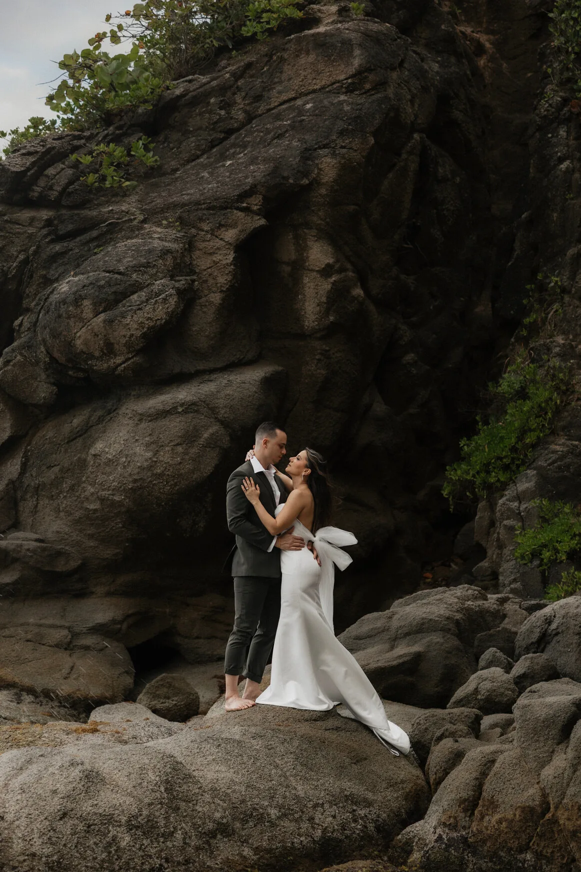 Bride and groom embracing on a rocky coastline