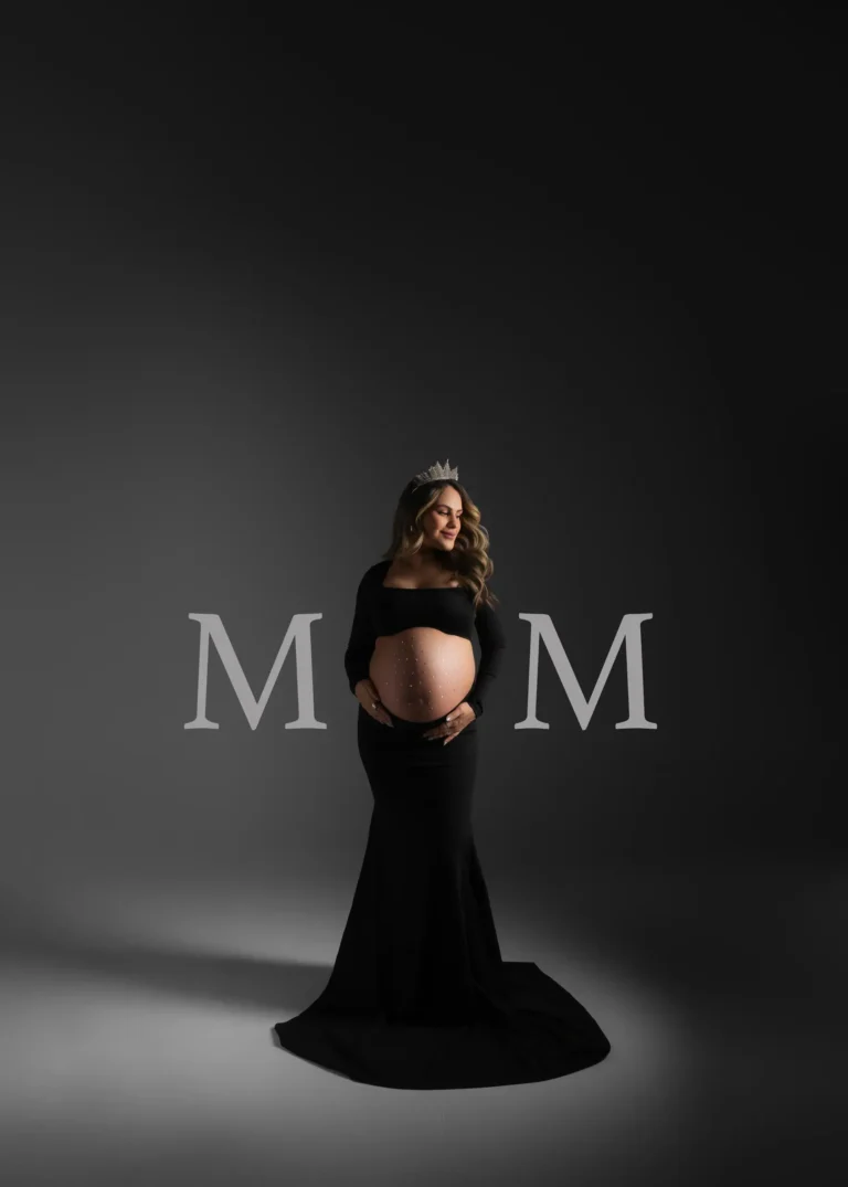 Pregnant woman in a black gown wearing a crown, dramatic studio portrait