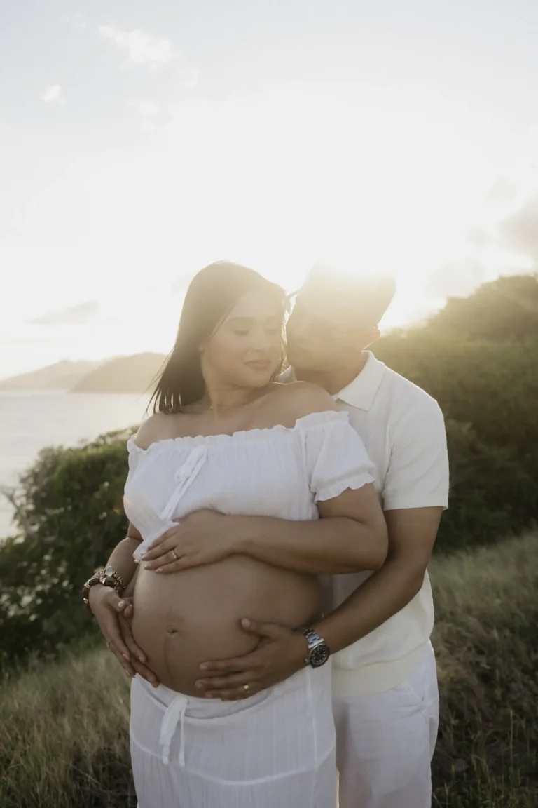 Couple embracing outdoors, woman cradling her pregnant belly