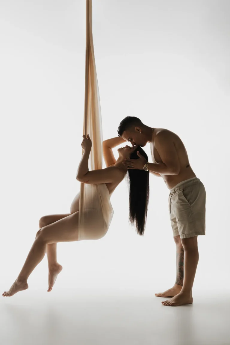 Pregnant woman suspended in a fabric sling with her partner assisting