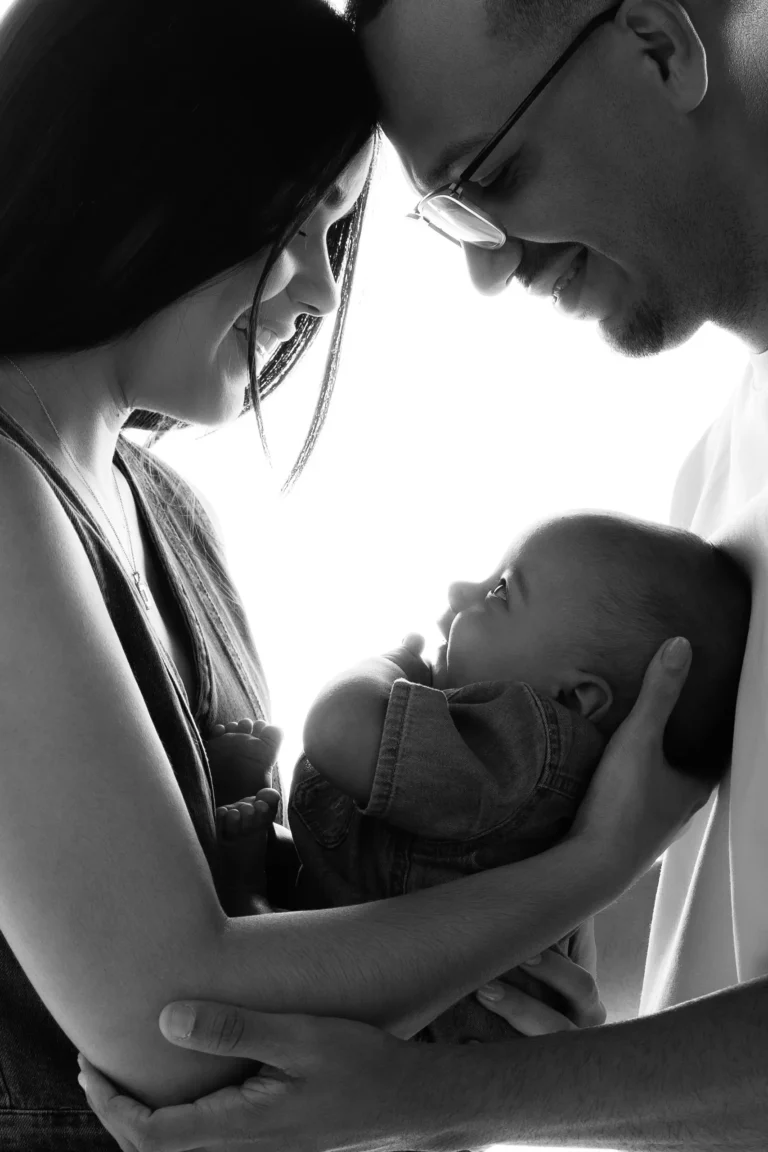 Black and white portrait of a father holding his newborn, foreheads close together