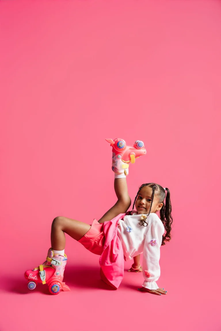 Child in colorful roller skates posing on a bright pink studio backdrop