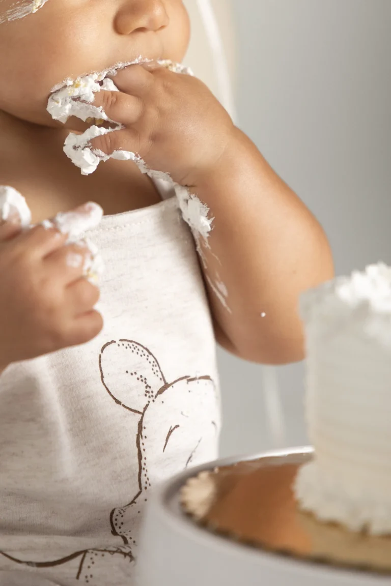 Toddler in a candid cake-smash portrait, hands covered in frosting