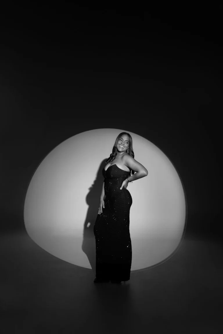 Woman in a black gown lit by a circular studio spotlight