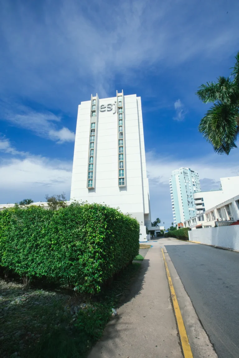 White high-rise building exterior with palm trees along a street